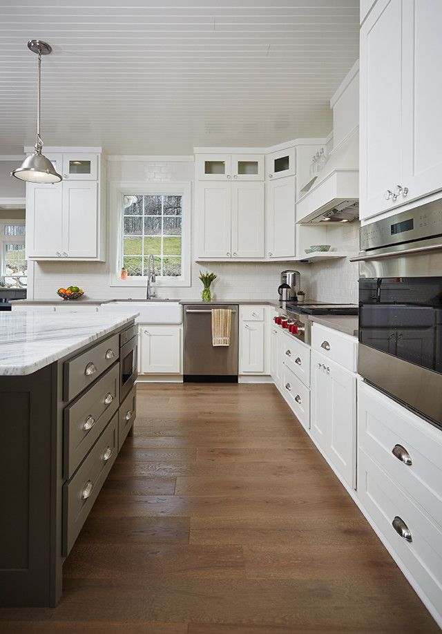 Foto på ett funkis kök, med en rustik diskho, vitt stänkskydd, rostfria vitvaror, mellanmörkt trägolv, skåp i shakerstil, vita skåp, marmorbänkskiva, stänkskydd i tunnelbanekakel och en köksö