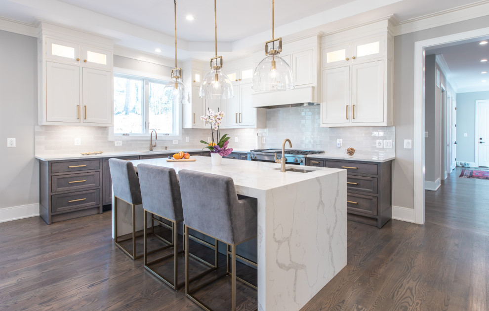 This is an example of a classic l-shaped kitchen in DC Metro with a submerged sink, recessed-panel cabinets, dark wood cabinets, white splashback, stainless steel appliances, dark hardwood flooring, an island, brown floors and white worktops.