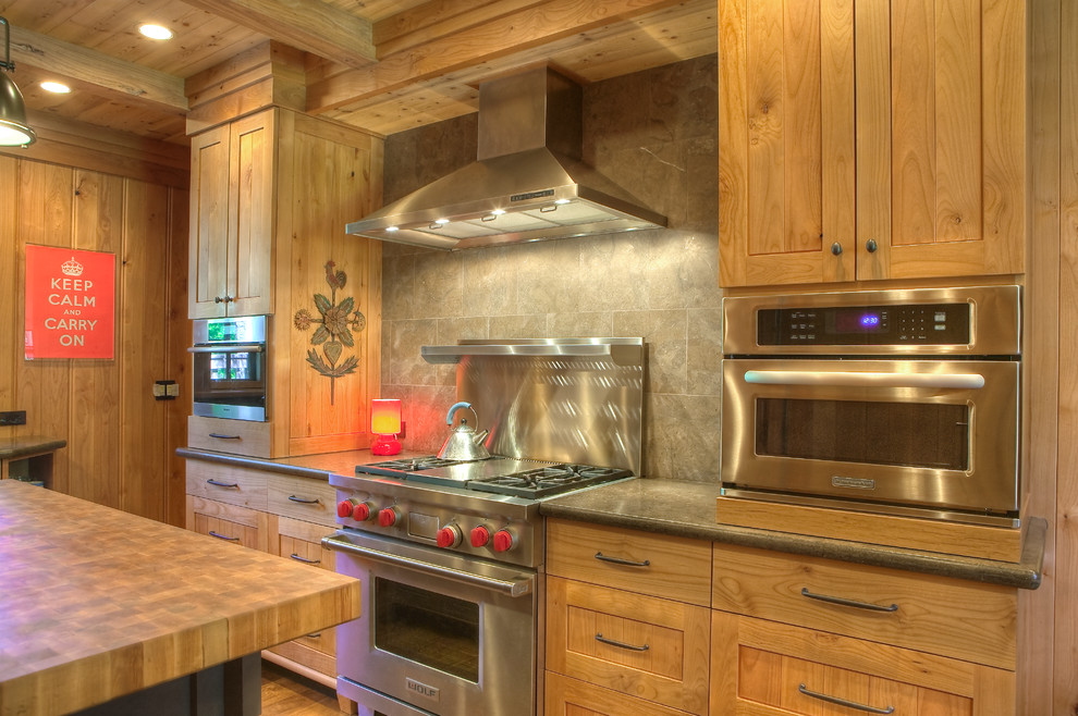 Diseño de cocina tradicional con armarios estilo shaker, puertas de armario de madera oscura y electrodomésticos de acero inoxidable