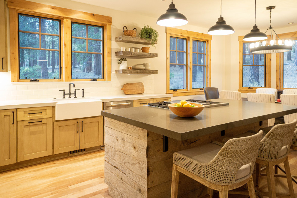 フェニックスにあるラスティックスタイルのおしゃれなアイランドキッチン (エプロンフロントシンク、シェーカースタイル扉のキャビネット、中間色木目調キャビネット、白いキッチンパネル、シルバーの調理設備、無垢フローリング、茶色い床、白いキッチンカウンター) の写真