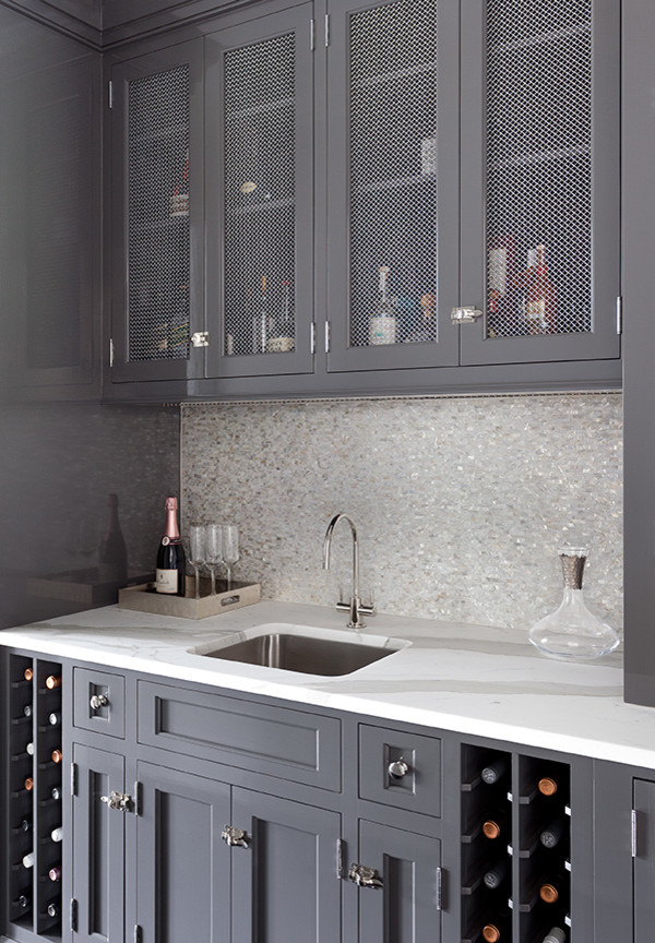 Exemple d'une arrière-cuisine chic avec un placard avec porte à panneau encastré, des portes de placard grises, plan de travail en marbre, une crédence beige, une crédence en mosaïque et un sol noir.
