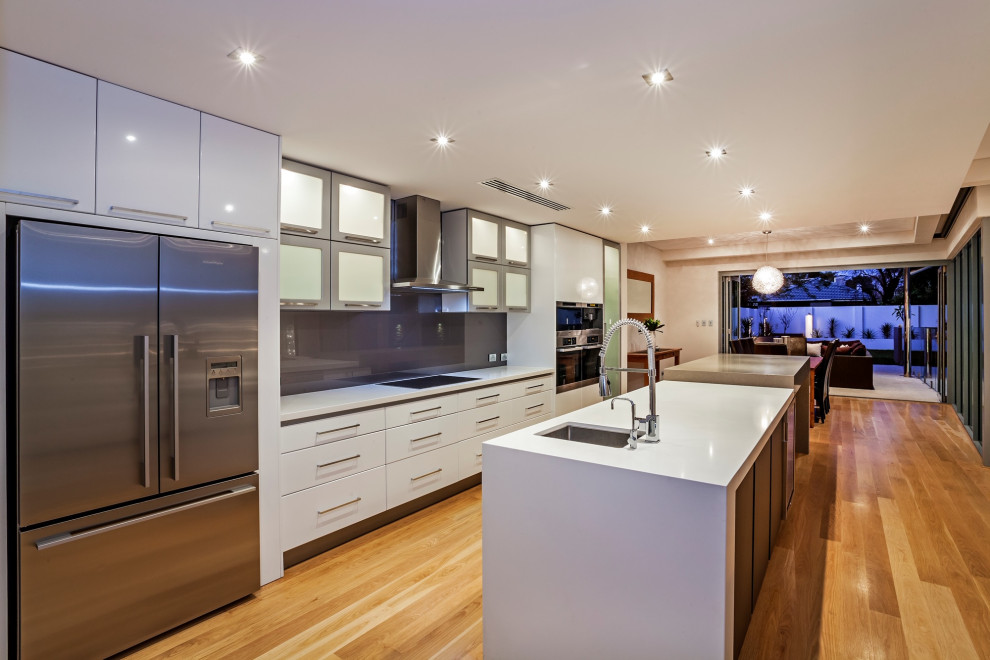 Immagine di una cucina moderna di medie dimensioni con lavello sottopiano, ante lisce, ante bianche, top in quarzo composito, paraspruzzi grigio e parquet chiaro