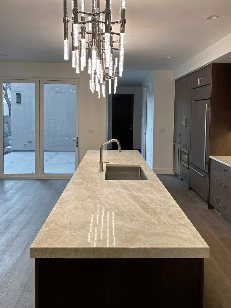 Large brown floor kitchen photo in Denver with flat-panel cabinets, quartzite countertops, beige backsplash, stone slab backsplash, an island and beige countertops