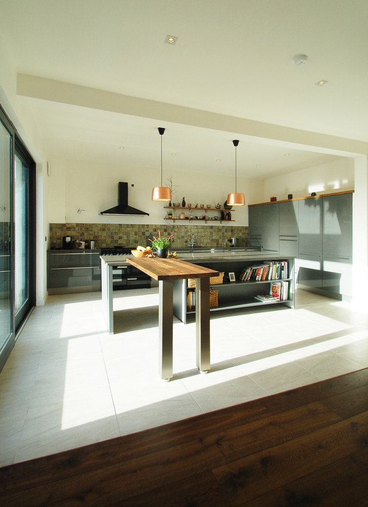 Modern inredning av ett stort kök, med en nedsänkt diskho, släta luckor, grå skåp, bänkskiva i kvarts, brunt stänkskydd, stänkskydd i keramik, svarta vitvaror, klinkergolv i keramik och en köksö