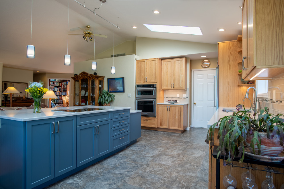 Klassisk inredning av ett mellanstort grå grått kök, med en undermonterad diskho, luckor med infälld panel, blå skåp, bänkskiva i kvarts, blått stänkskydd, stänkskydd i keramik, rostfria vitvaror, vinylgolv, en köksö och blått golv