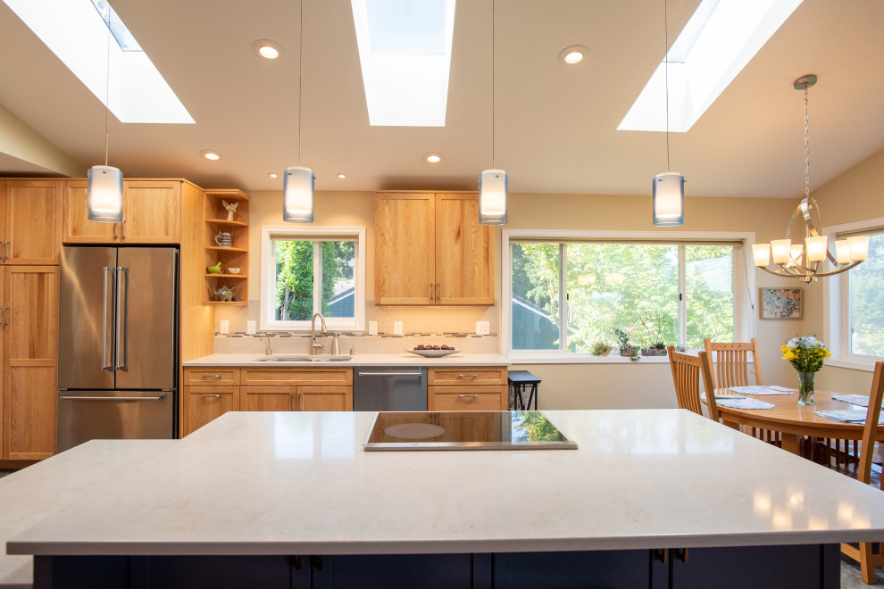 Klassisk inredning av ett mellanstort grå grått kök, med en undermonterad diskho, luckor med infälld panel, blå skåp, bänkskiva i kvarts, blått stänkskydd, stänkskydd i keramik, rostfria vitvaror, vinylgolv, en köksö och blått golv