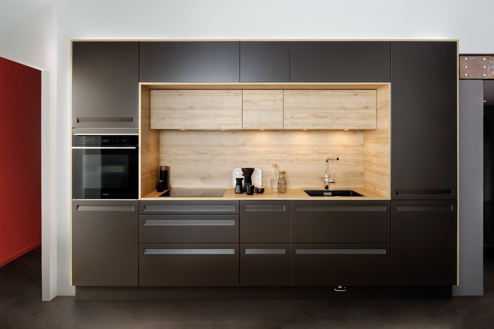 Idéer för små funkis linjära brunt kök och matrum, med en enkel diskho, luckor med infälld panel, bruna skåp, laminatbänkskiva, brunt stänkskydd, stänkskydd i trä, svarta vitvaror och en köksö