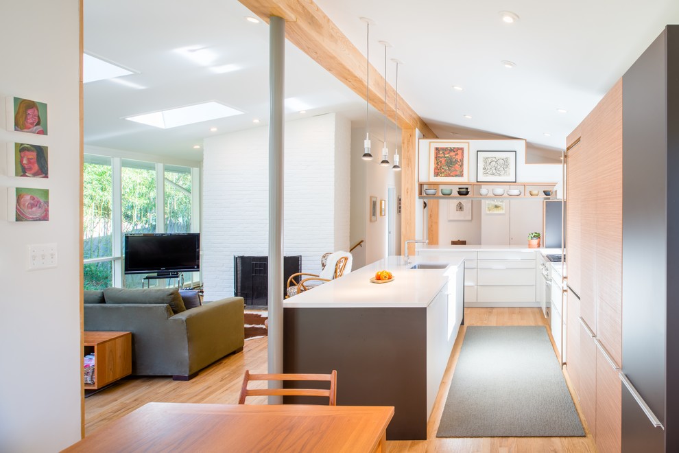 Idéer för ett modernt kök, med en undermonterad diskho, släta luckor, vita skåp, mellanmörkt trägolv, en halv köksö och brunt golv