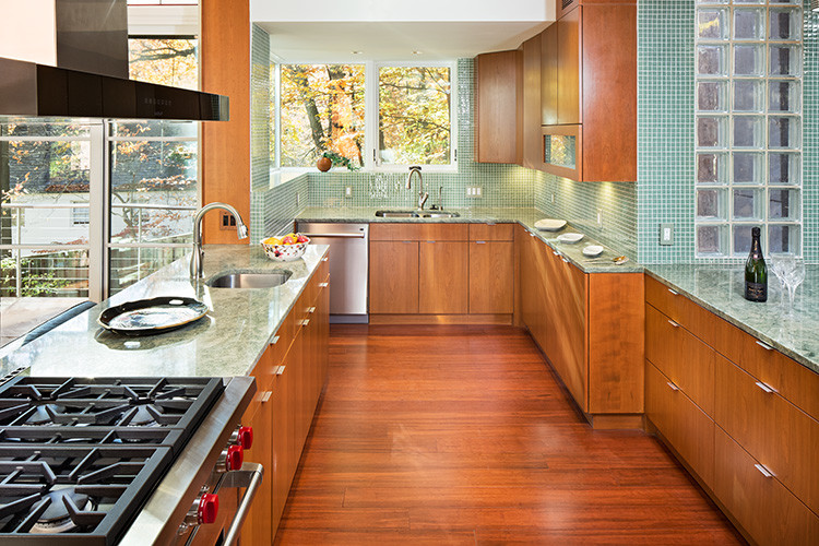 Exempel på ett stort modernt grön grönt u-kök, med en dubbel diskho, släta luckor, skåp i mellenmörkt trä, marmorbänkskiva, grönt stänkskydd, stänkskydd i glaskakel, rostfria vitvaror, mellanmörkt trägolv, en halv köksö och brunt golv