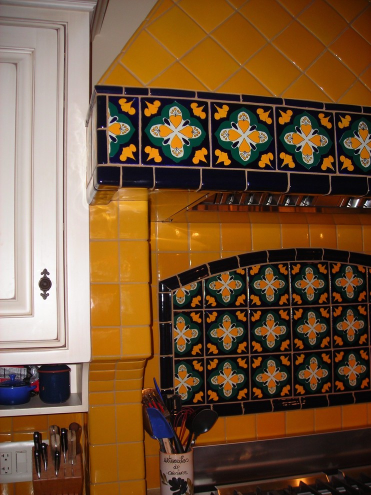 Photo of a medium sized mediterranean single-wall kitchen/diner in Sacramento with raised-panel cabinets, white cabinets, multi-coloured splashback, ceramic splashback, coloured appliances, an island and black worktops.