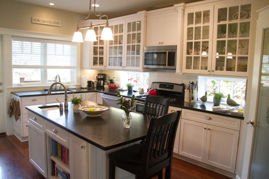 Klassisk inredning av ett mellanstort kök, med en undermonterad diskho, luckor med glaspanel, vita skåp, granitbänkskiva, vitt stänkskydd, stänkskydd i glaskakel, rostfria vitvaror, mörkt trägolv och en köksö