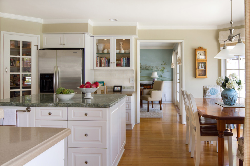 Klassische Wohnküche mit profilierten Schrankfronten, weißen Schränken, Küchenrückwand in Weiß, Rückwand aus Metrofliesen und Küchengeräten aus Edelstahl in Los Angeles