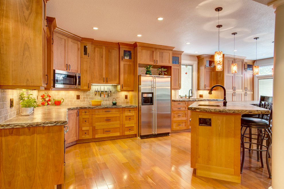 Foto på ett stort vintage kök, med en dubbel diskho, skåp i shakerstil, skåp i ljust trä, granitbänkskiva, brunt stänkskydd, stänkskydd i stenkakel, rostfria vitvaror, ljust trägolv och en köksö