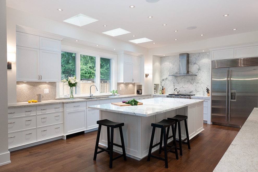 This is an example of a traditional u-shaped kitchen in Vancouver with a submerged sink, recessed-panel cabinets, white cabinets, marble worktops, white splashback, stainless steel appliances and marble splashback.