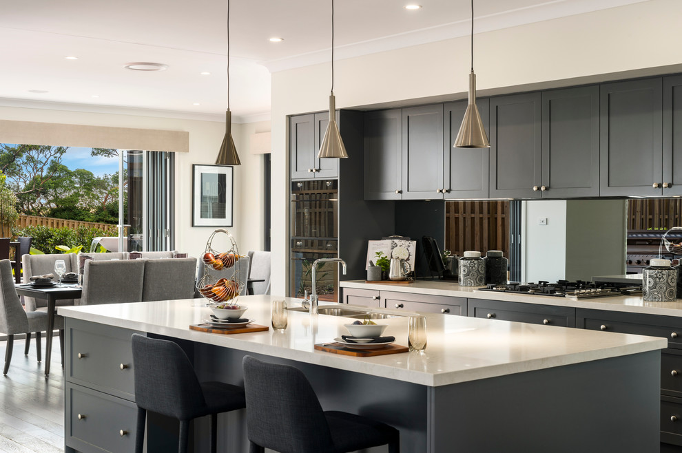 This is an example of a large contemporary single-wall open plan kitchen in Brisbane with a submerged sink, shaker cabinets, grey cabinets, engineered stone countertops, metallic splashback, mirror splashback, stainless steel appliances, dark hardwood flooring and an island.