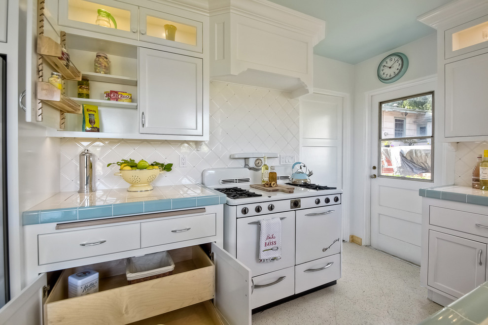 Enclosed kitchen - mid-sized transitional galley terrazzo floor enclosed kitchen idea in San Diego with a double-bowl sink, recessed-panel cabinets, white cabinets, tile countertops, white backsplash, ceramic backsplash, white appliances and no island