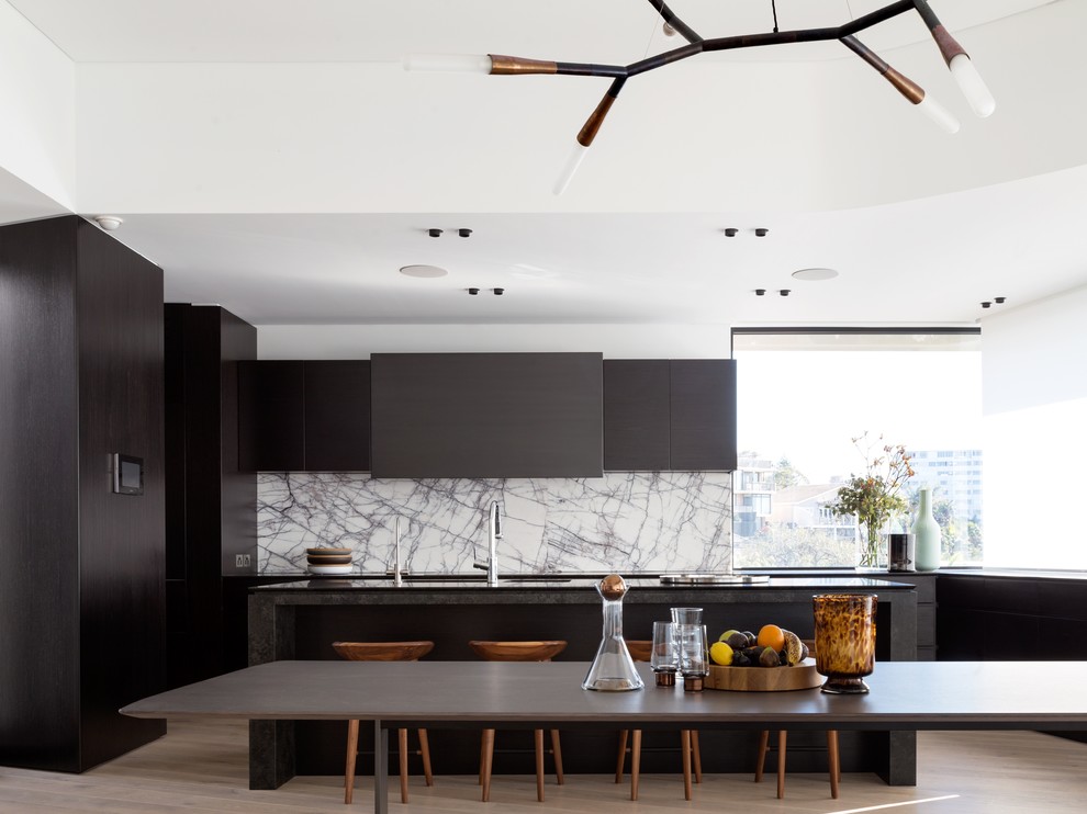 Photo of a modern galley kitchen/diner in Sydney with an island, flat-panel cabinets, dark wood cabinets, light hardwood flooring and marble splashback.