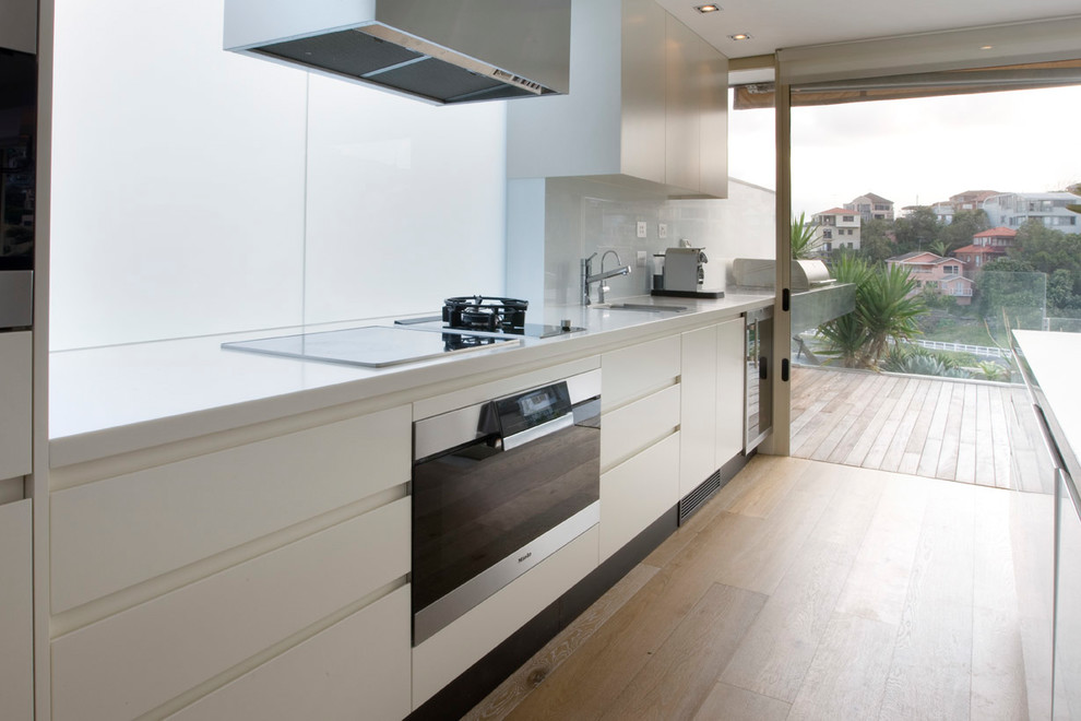 Zweizeilige, Mittelgroße Moderne Wohnküche mit Unterbauwaschbecken, flächenbündigen Schrankfronten, Marmor-Arbeitsplatte, Küchenrückwand in Weiß, Glasrückwand, Küchengeräten aus Edelstahl, hellem Holzboden und Kücheninsel in Sydney