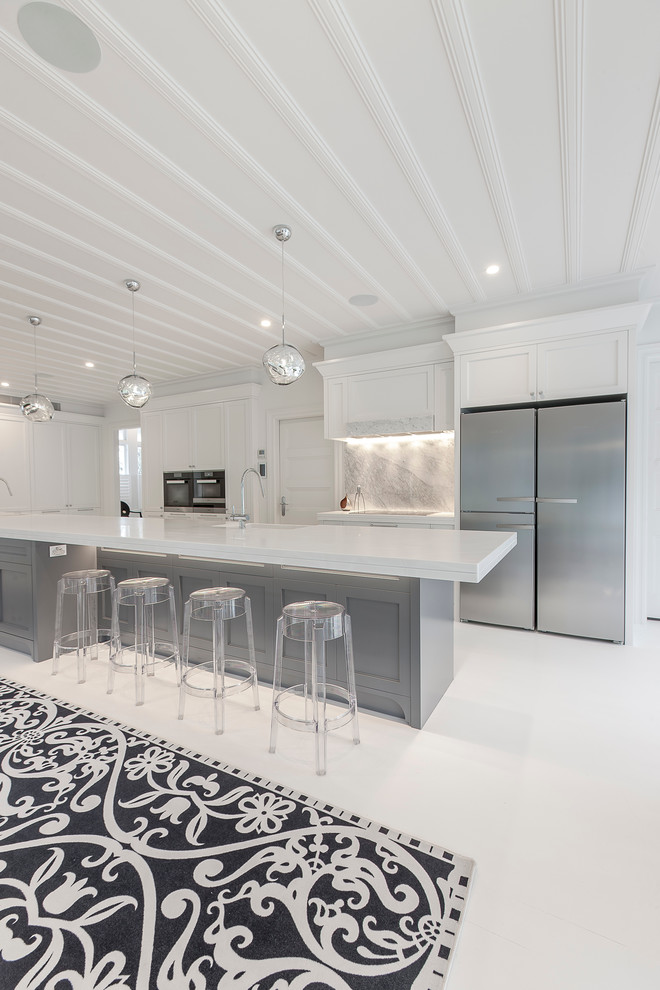 This is an example of an expansive classic galley kitchen/diner in Auckland with a belfast sink, recessed-panel cabinets, white cabinets, composite countertops, multi-coloured splashback, stone slab splashback, black appliances, painted wood flooring and an island.