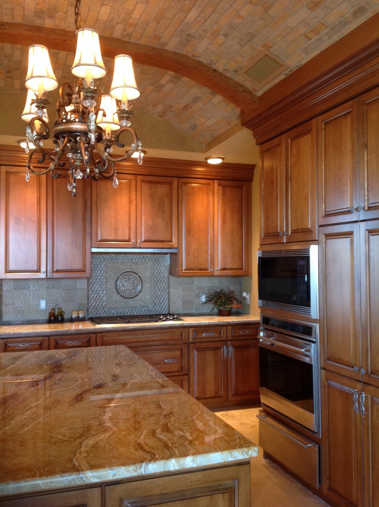 This is an example of a large traditional u-shaped kitchen/diner in Tampa with a submerged sink, raised-panel cabinets, medium wood cabinets, granite worktops, beige splashback, stone tiled splashback, stainless steel appliances, travertine flooring and an island.