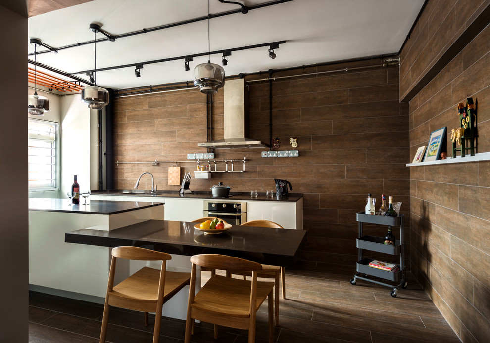 Idée de décoration pour une cuisine urbaine avec un évier encastré, un placard à porte plane, des portes de placard blanches, une crédence marron, un électroménager en acier inoxydable et un sol en bois brun.