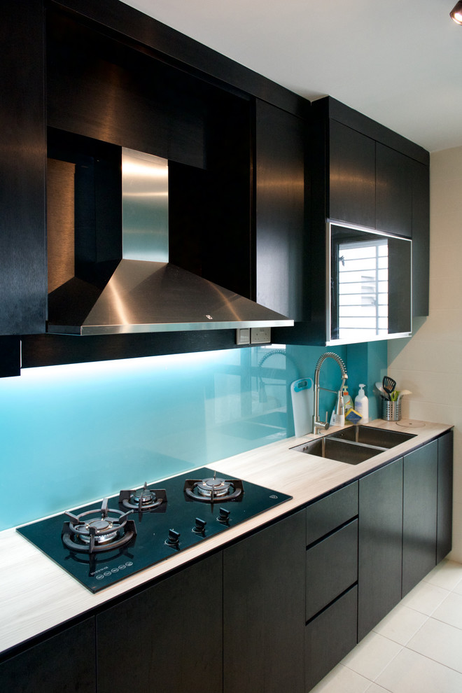 Cette image montre une cuisine design avec des portes de placard noires, une crédence bleue, un sol en carrelage de porcelaine et papier peint.