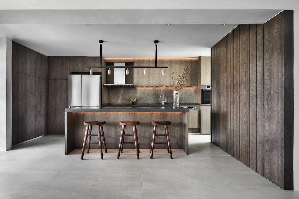 Design ideas for a contemporary u-shaped kitchen/diner in Singapore with flat-panel cabinets, dark wood cabinets, brown splashback, stainless steel appliances, an island, beige floors and black worktops.