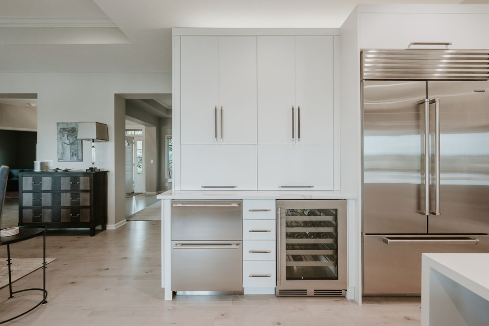 Foto de cocinas en L contemporánea de tamaño medio con fregadero bajoencimera, armarios con paneles lisos, encimera de cuarcita, salpicadero verde, salpicadero de azulejos de cerámica, electrodomésticos de acero inoxidable, suelo de madera clara, una isla, suelo gris y encimeras grises