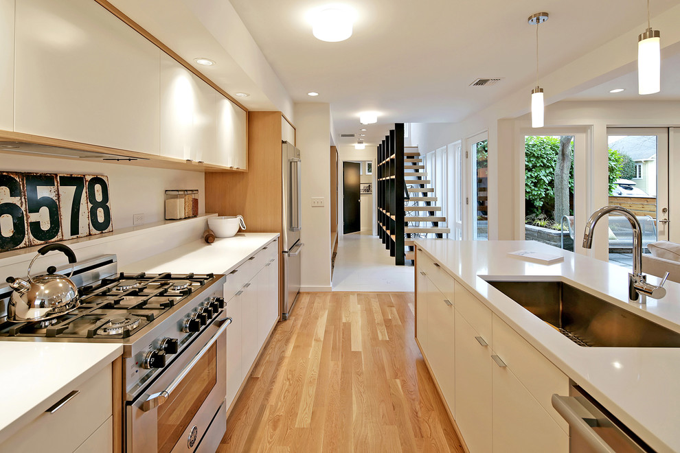 Cette photo montre une cuisine moderne avec un placard à porte plane, des portes de placard blanches, un plan de travail en quartz modifié et îlot.