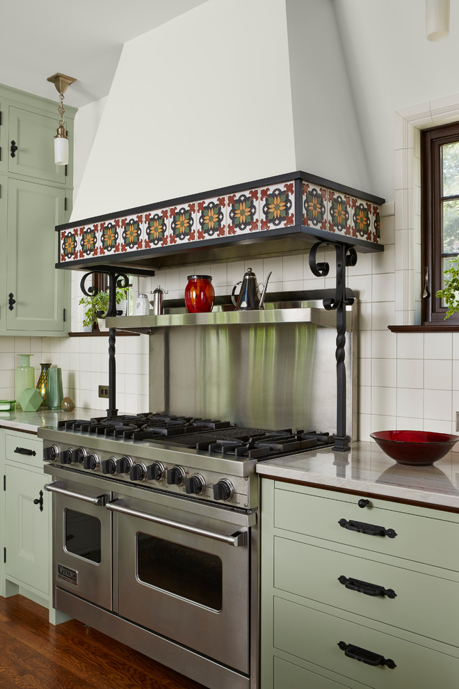 Foto på ett medelhavsstil kök, med en dubbel diskho, luckor med infälld panel, gröna skåp, bänkskiva i kvartsit, vitt stänkskydd, stänkskydd i keramik, rostfria vitvaror, mörkt trägolv, en köksö och brunt golv