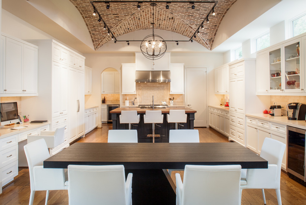 Eat-in kitchen - large transitional u-shaped medium tone wood floor and brown floor eat-in kitchen idea in Houston with a farmhouse sink, raised-panel cabinets, white cabinets, wood countertops, beige backsplash, stone tile backsplash, paneled appliances and an island