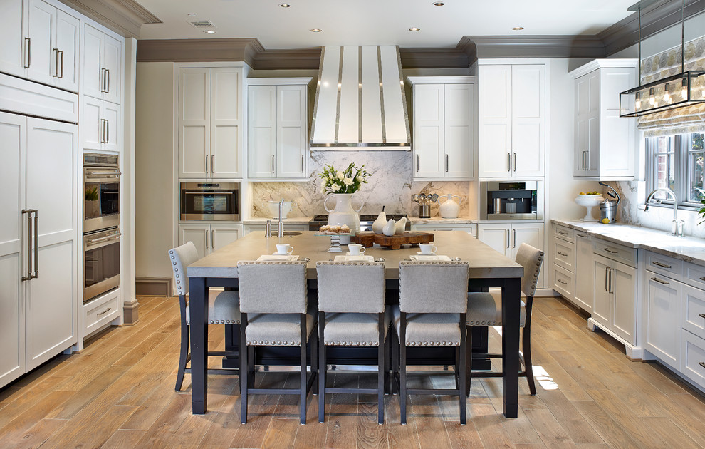 Example of a large transitional l-shaped light wood floor eat-in kitchen design in Houston with white cabinets, concrete countertops, white backsplash, stone slab backsplash, shaker cabinets and paneled appliances