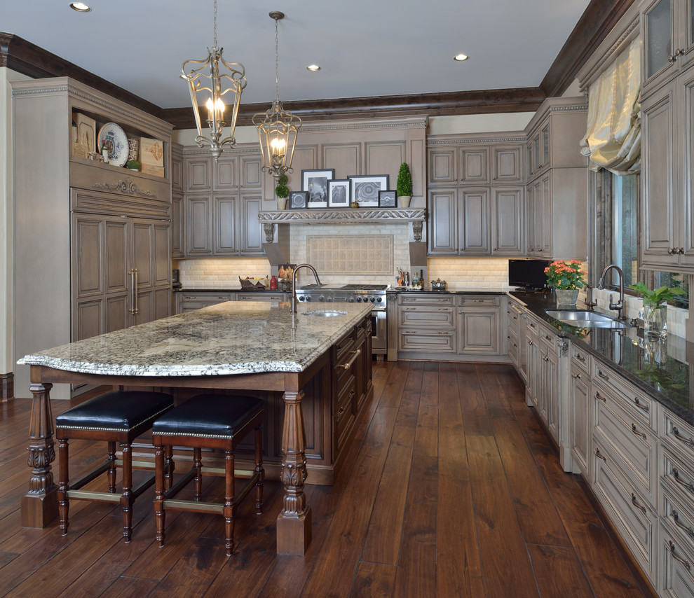 Inspiration for a large timeless l-shaped medium tone wood floor open concept kitchen remodel in Houston with a double-bowl sink, gray cabinets, granite countertops, beige backsplash, stone tile backsplash, paneled appliances and an island