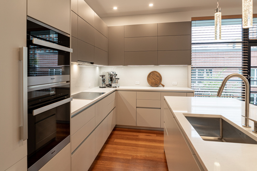 Foto på ett mellanstort funkis vit kök, med en undermonterad diskho, släta luckor, beige skåp, bänkskiva i kvarts, vitt stänkskydd, integrerade vitvaror, mellanmörkt trägolv, en halv köksö och brunt golv