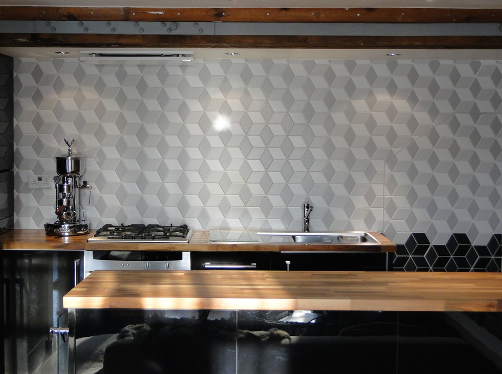 Moderne Küche mit flächenbündigen Schrankfronten, schwarzen Schränken, Arbeitsplatte aus Holz, Küchenrückwand in Grau, Rückwand aus Mosaikfliesen, Küchengeräten aus Edelstahl und Kücheninsel in London