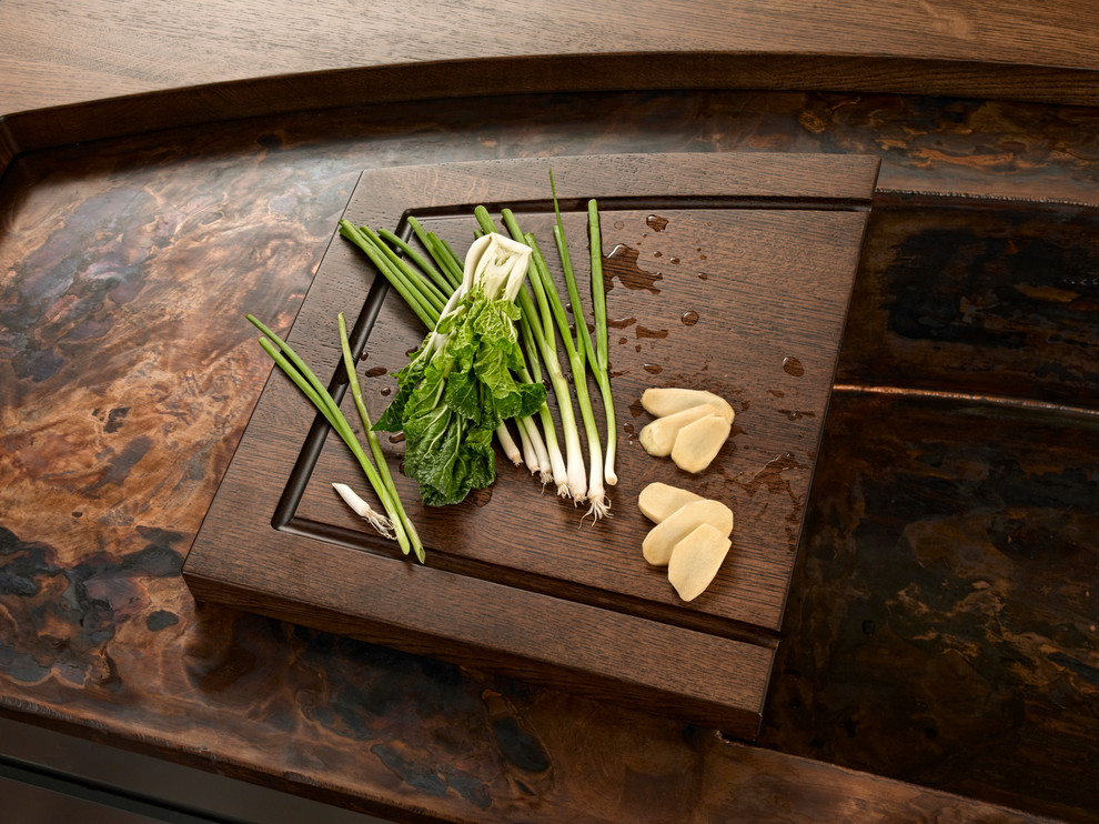 Aménagement d'une cuisine asiatique en bois clair avec un plan de travail en cuivre, une crédence verte, une crédence en dalle de pierre et un électroménager noir.