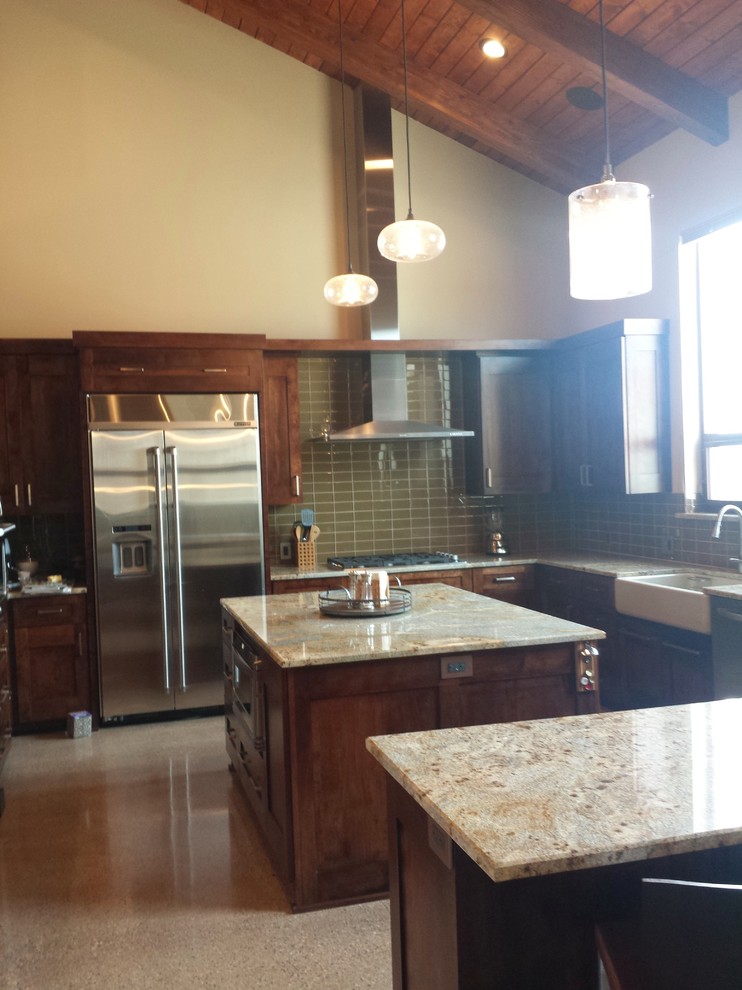 Bild på ett stort vintage kök, med en rustik diskho, luckor med infälld panel, skåp i mörkt trä, granitbänkskiva, grönt stänkskydd, stänkskydd i glaskakel, rostfria vitvaror, betonggolv och en köksö