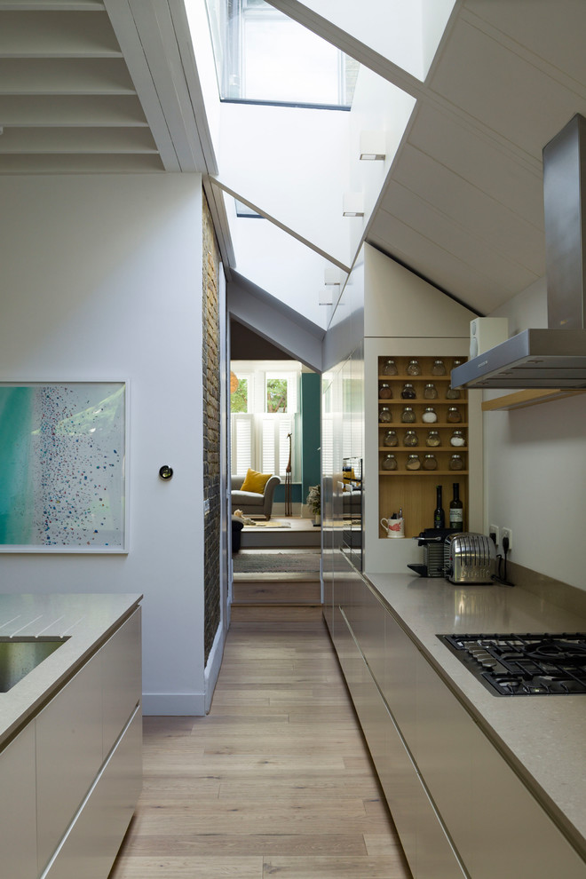 Esempio di una cucina design con ante lisce, ante bianche, top in superficie solida, parquet chiaro e pavimento marrone