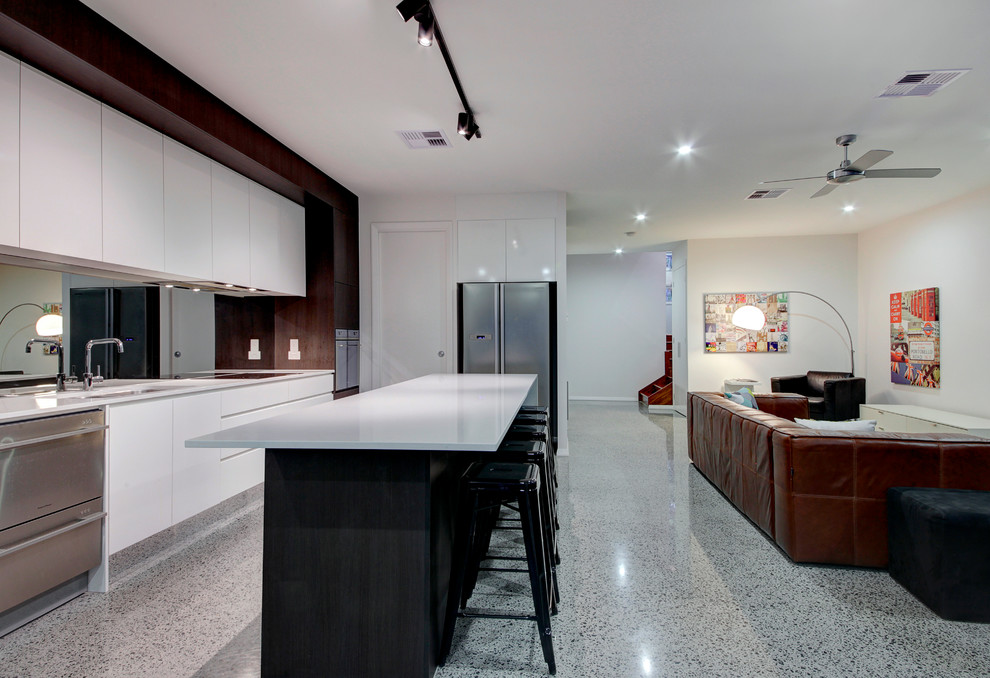 Bild på ett mellanstort funkis kök, med en undermonterad diskho, släta luckor, vita skåp, laminatbänkskiva, stänkskydd med metallisk yta, glaspanel som stänkskydd, rostfria vitvaror, betonggolv och en köksö