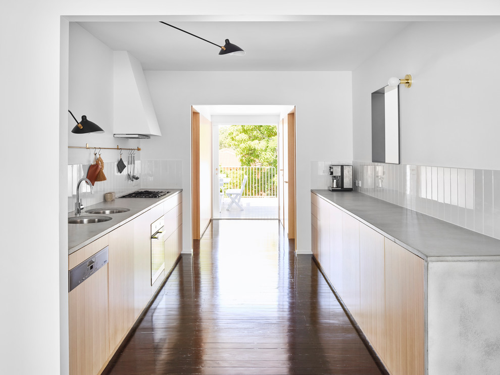 Foto di una piccola cucina parallela minimal con ante in legno chiaro, top in cemento, parquet scuro e pavimento nero