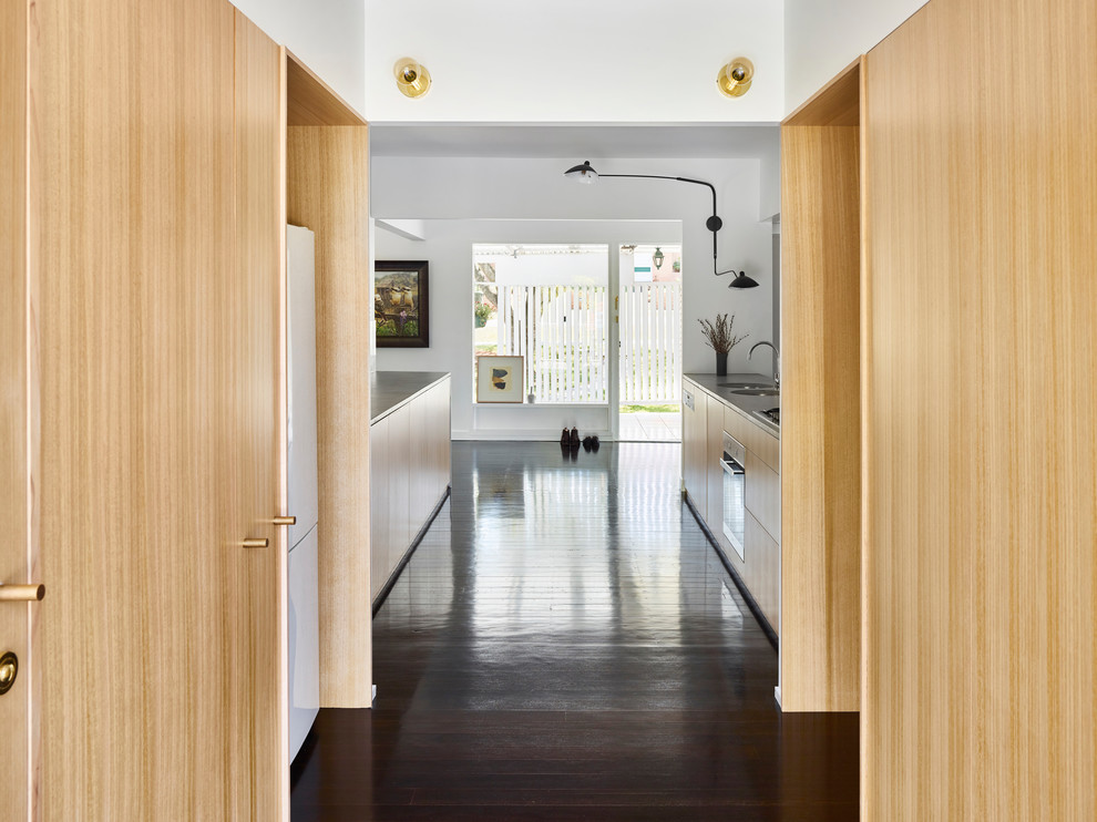 Immagine di una piccola cucina parallela contemporanea con ante in legno chiaro, top in cemento, parquet scuro e pavimento nero