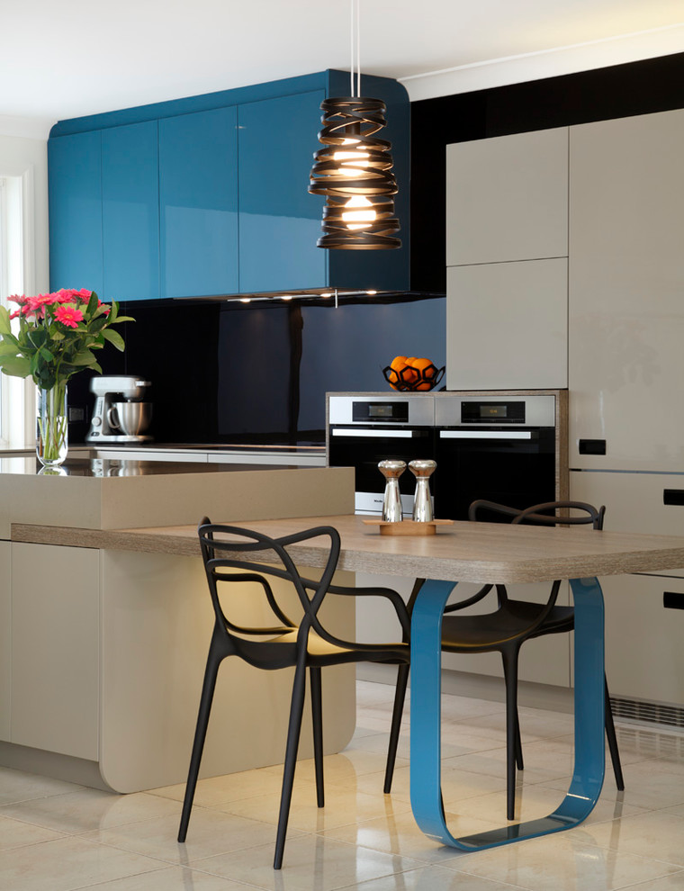 Стильный дизайн: кухня среднего размера в современном стиле с обеденным столом, плоскими фасадами, синими фасадами, черным фартуком, фартуком из стекла, техникой под мебельный фасад и бежевым полом - последний тренд