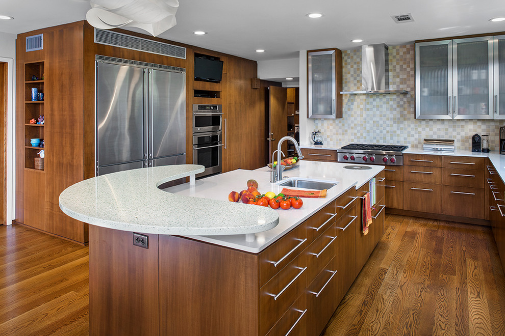 Moderne Küche in L-Form mit Unterbauwaschbecken, dunklen Holzschränken, Mineralwerkstoff-Arbeitsplatte, Küchenrückwand in Beige, Küchengeräten aus Edelstahl und braunem Holzboden in Austin