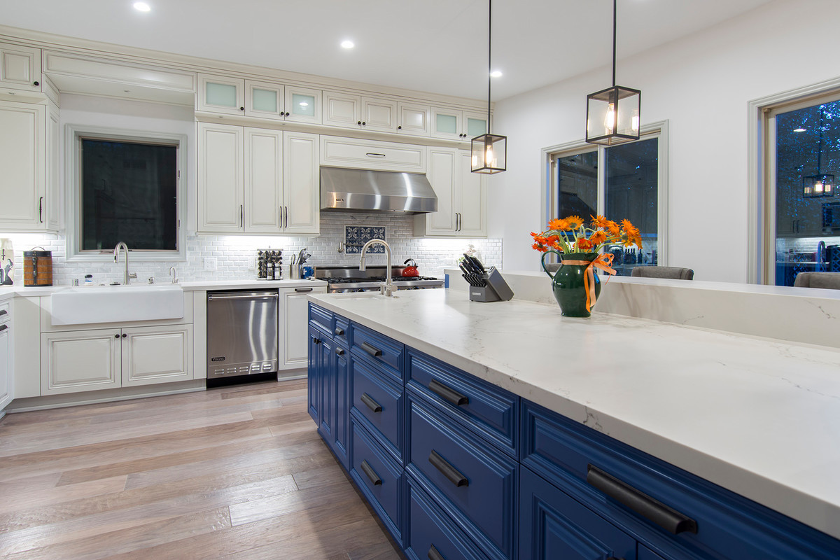 ロサンゼルスにある高級な中くらいなコンテンポラリースタイルのおしゃれなキッチン (エプロンフロントシンク、レイズドパネル扉のキャビネット、白いキャビネット、珪岩カウンター、白いキッチンパネル、セラミックタイルのキッチンパネル、シルバーの調理設備、淡色無垢フローリング、ベージュの床) の写真