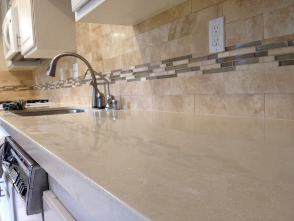 Example of a large classic enclosed kitchen design in Los Angeles with a double-bowl sink, raised-panel cabinets, white cabinets, limestone countertops, beige backsplash and stone tile backsplash