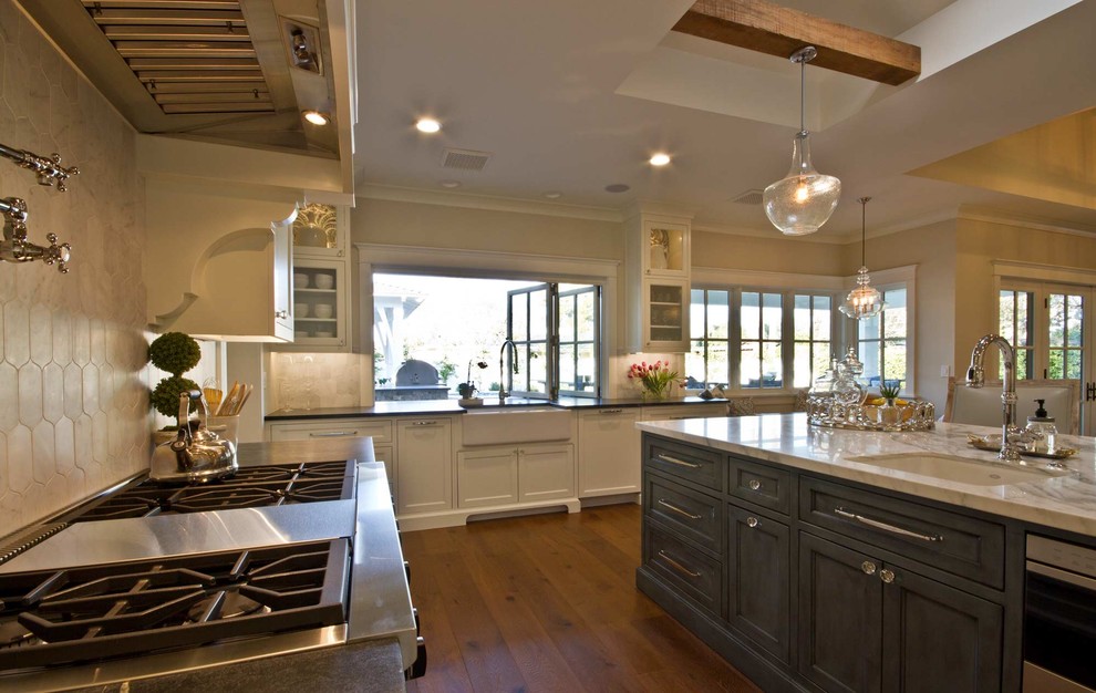 Klassisk inredning av ett mellanstort linjärt kök och matrum, med en rustik diskho, luckor med infälld panel, vita skåp, marmorbänkskiva, rostfria vitvaror, mörkt trägolv, en köksö och brunt golv