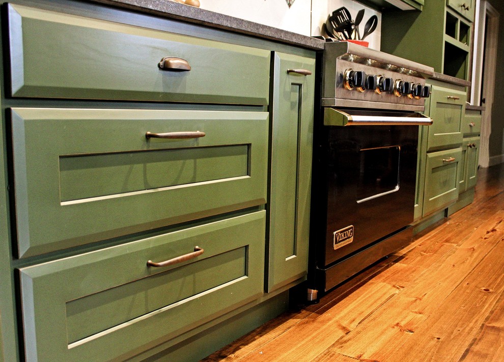 Inredning av ett eklektiskt stort kök, med en rustik diskho, skåp i shakerstil, gröna skåp, granitbänkskiva, grönt stänkskydd, stänkskydd i keramik, svarta vitvaror, mellanmörkt trägolv, en köksö och brunt golv