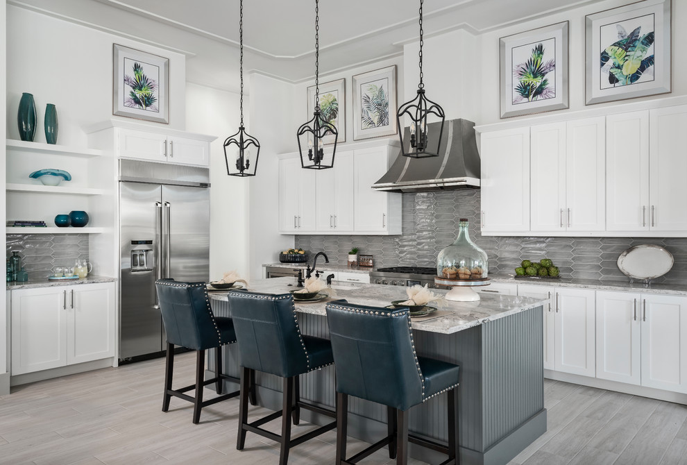 Example of a mid-sized beach style porcelain tile kitchen design in Miami with an undermount sink, white cabinets, quartzite countertops, gray backsplash, stainless steel appliances, an island, gray countertops and shaker cabinets