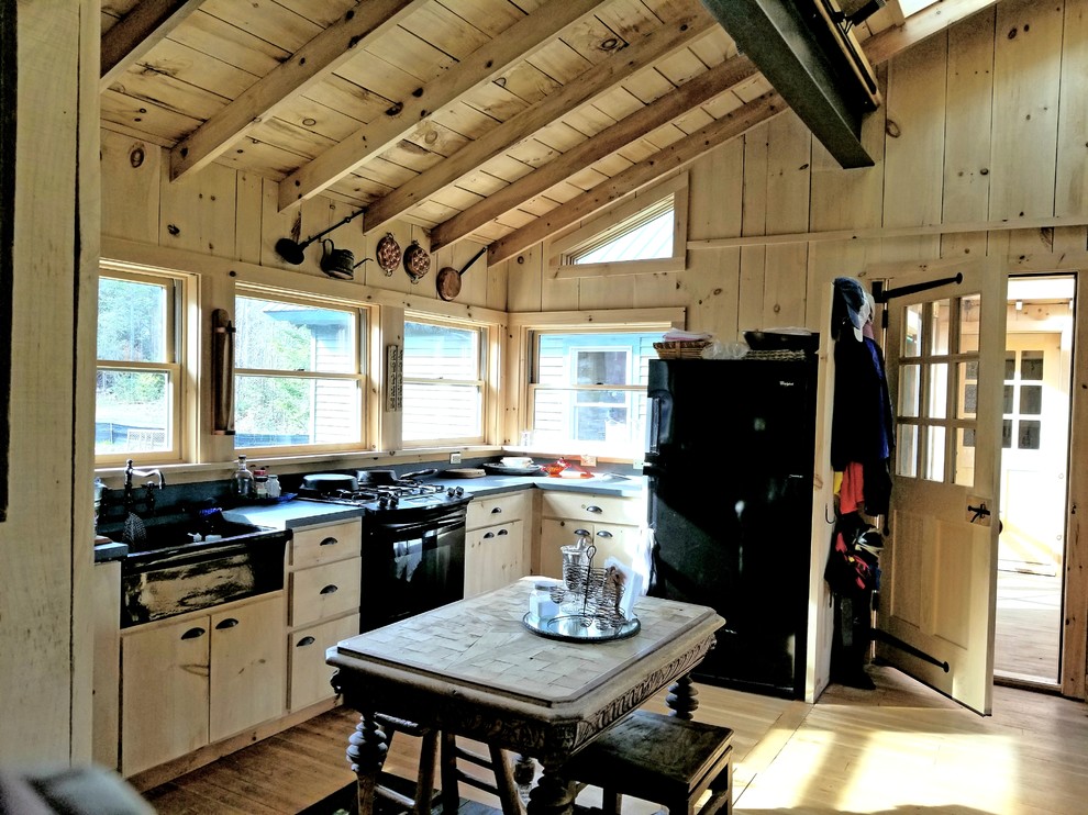 Immagine di una cucina minimalista di medie dimensioni con lavello stile country, ante lisce, ante in legno chiaro, top in saponaria, paraspruzzi grigio e pavimento in legno massello medio