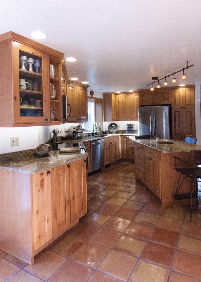 Rustik inredning av ett mellanstort kök, med en undermonterad diskho, luckor med upphöjd panel, skåp i mellenmörkt trä, granitbänkskiva, grönt stänkskydd, stänkskydd i sten, rostfria vitvaror, klinkergolv i terrakotta och en köksö
